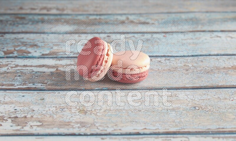 45º Shot of two Pink Litchi Raspberry macarons on light blue wooden background