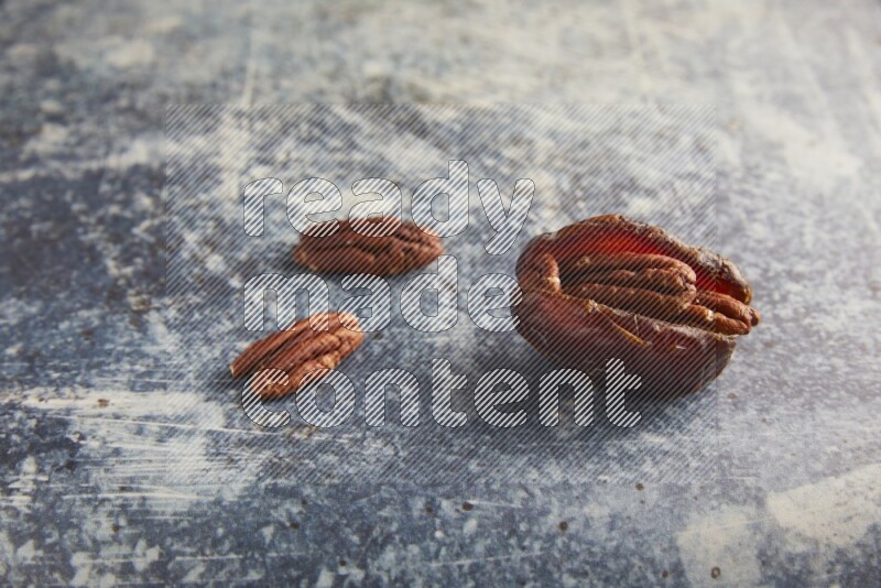 pecan stuffed madjoul date on a rustic blue background