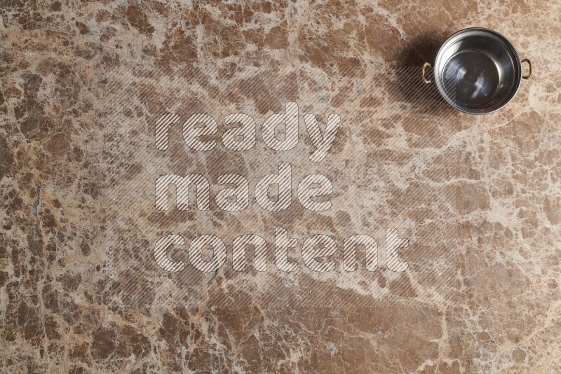 A small copper pot on beige marble background