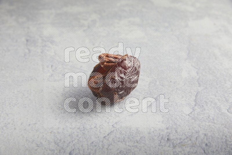 pecan stuffed madjoul date on a light grey background
