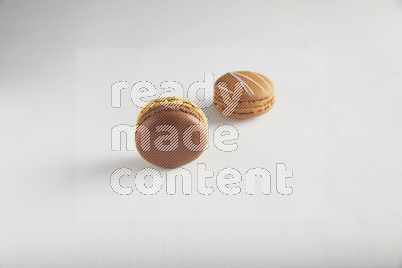 45º Shot of of two assorted Brown Irish Cream, and Yellow, and Brown Chai Latte macarons on white background