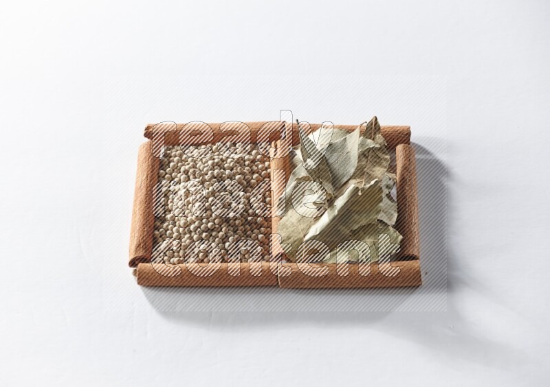 2 squares of cinnamon sticks full of white pepper and bay laurel leaves on white flooring
