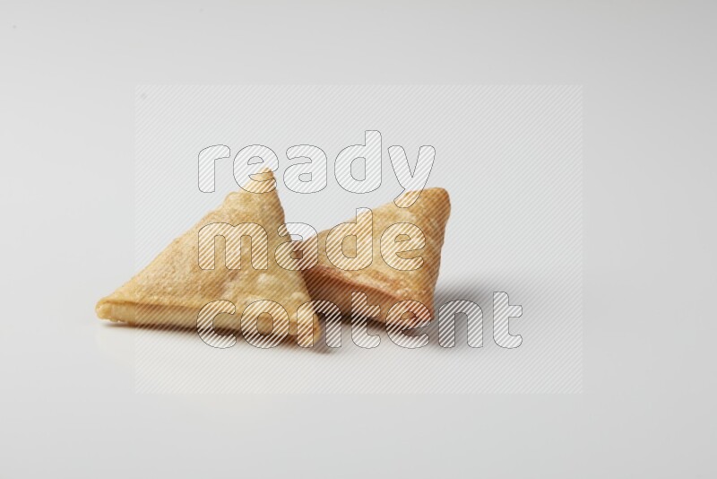 Two fried sambosas on a white background