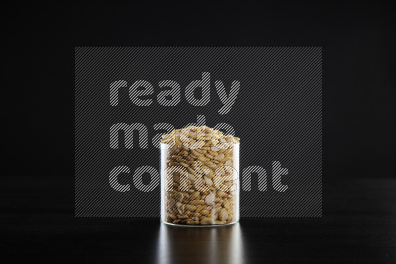 Crushed beans in a glass jar on black background