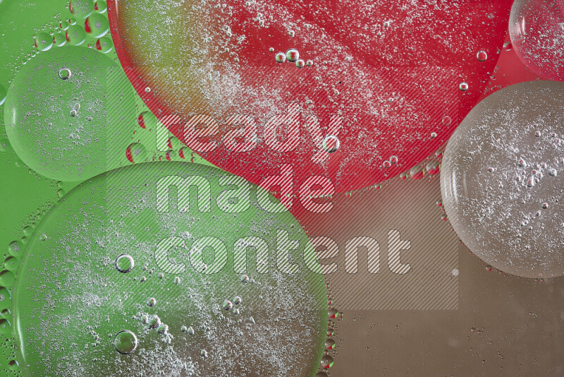 Close-ups of abstract oil bubbles on water surface in shades of brown, green and red