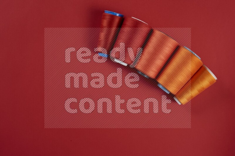 مجموعة من أدوات الخياطة والتفصيل برتقالية اللون على خلفية حمراء