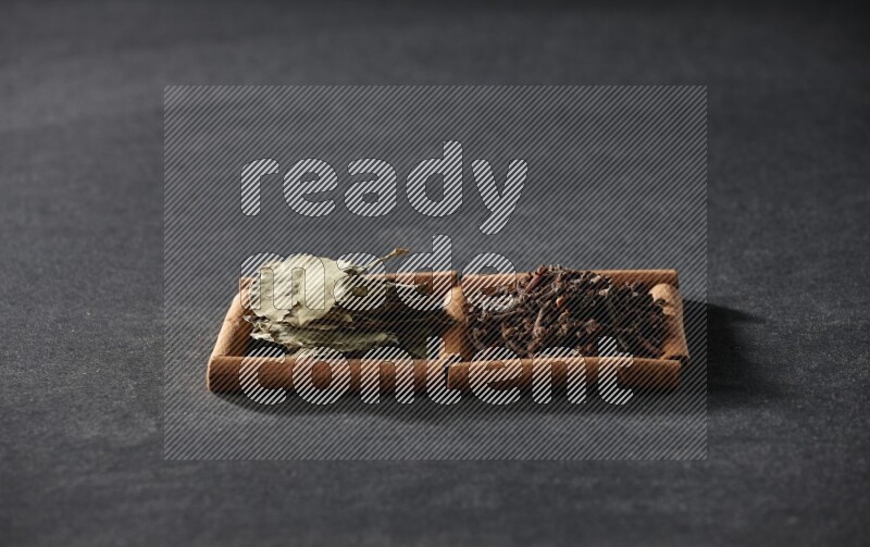 2 squares of cinnamon sticks full of cloves and bay laurel leaves on black flooring