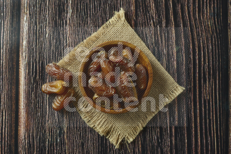 Dates in different bowls (wooden, pottery and glass) on wooden background