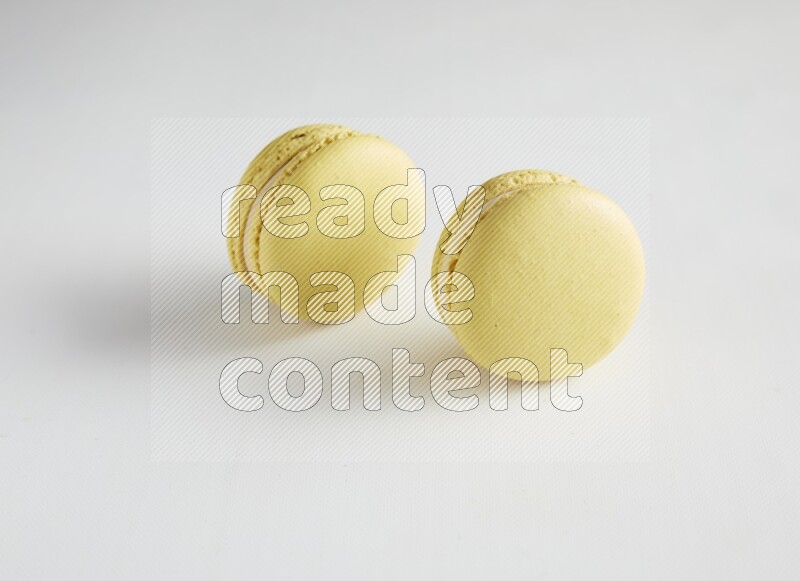 45º Shot of two Yellow Lime macarons on white background