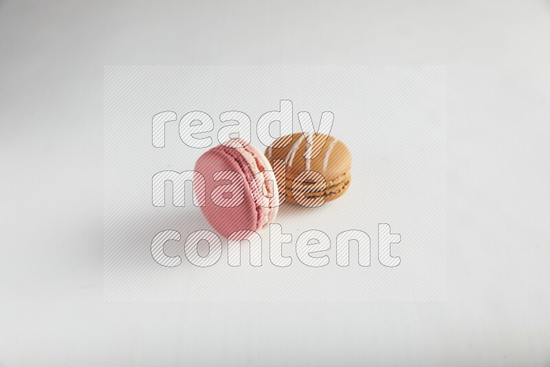 45º Shot of of two assorted Brown Irish Cream, and Pink Litchi Raspberry macarons on white background