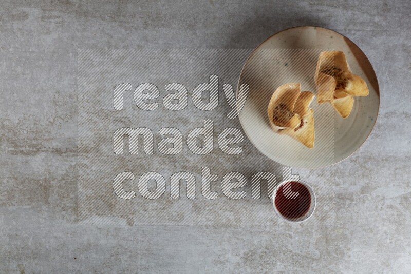 wonton cups with soy sauce ramkin on multi colored pottery on grey textured counter top