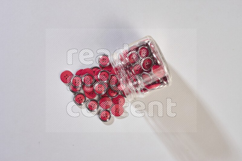 Colored buttons in a glass jar on grey background