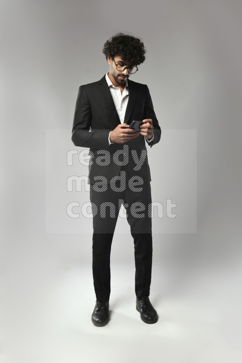 A man wearing formal standing and texting on the phone on white background