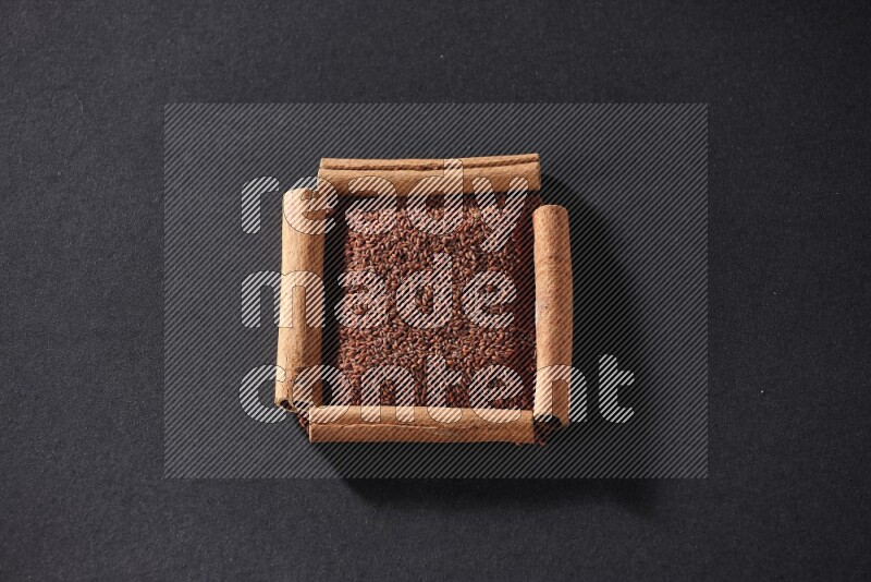 A single square of cinnamon sticks full of garden cress on black flooring