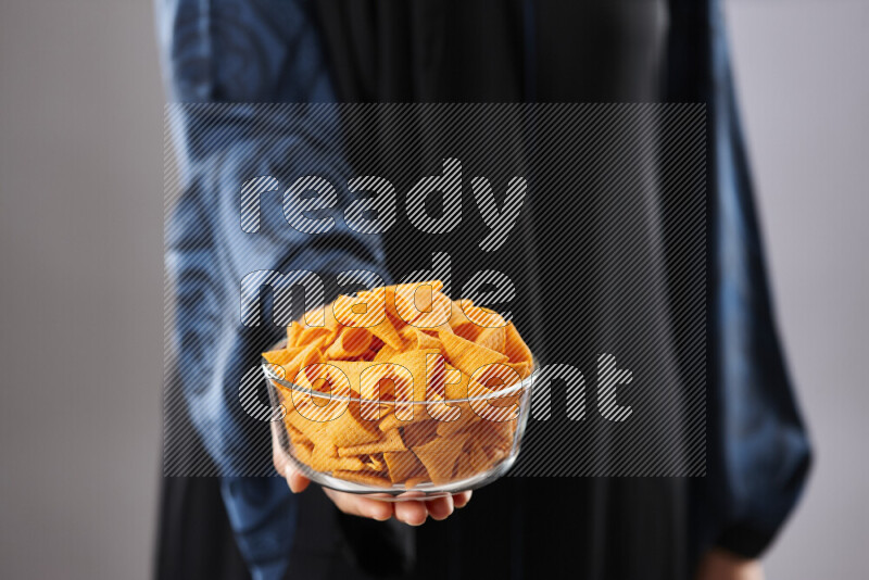 Woman in abaya holding different kinds of snacks in different positions