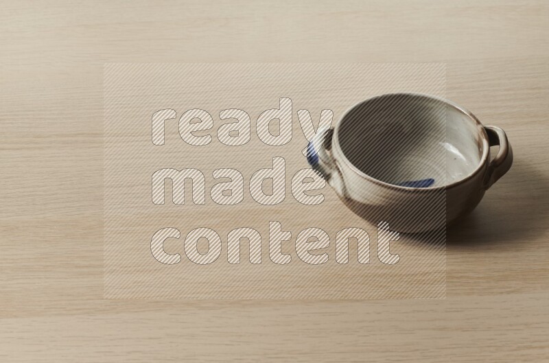 A multicolored pottery bowl on light wooden background