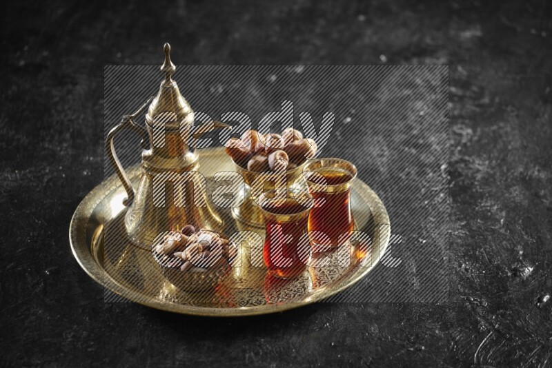 Nuts with dates and a drink on a metal tray in a dark setup