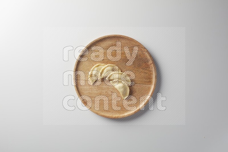 Four Sambosas on a wooden round plate on a white background