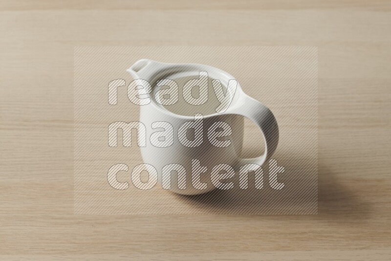A ceramic milk jug on light wooden background