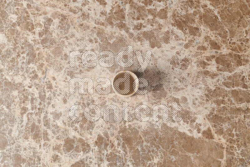 A pottery cup on beige marble background