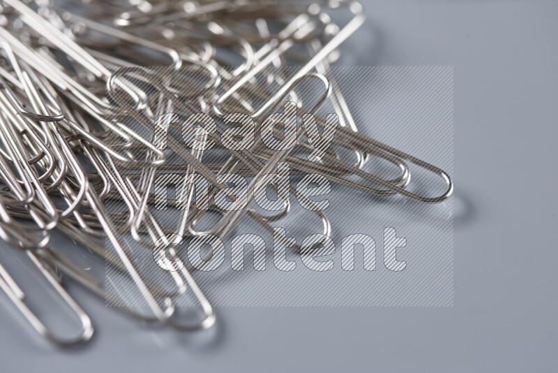 Silver paper clips isolated on a grey background