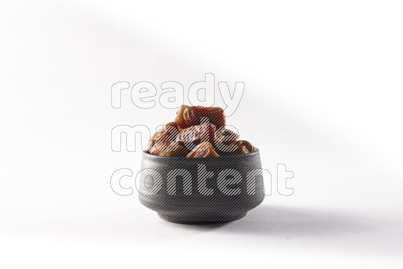 Dates in a black pottery bowl on white background