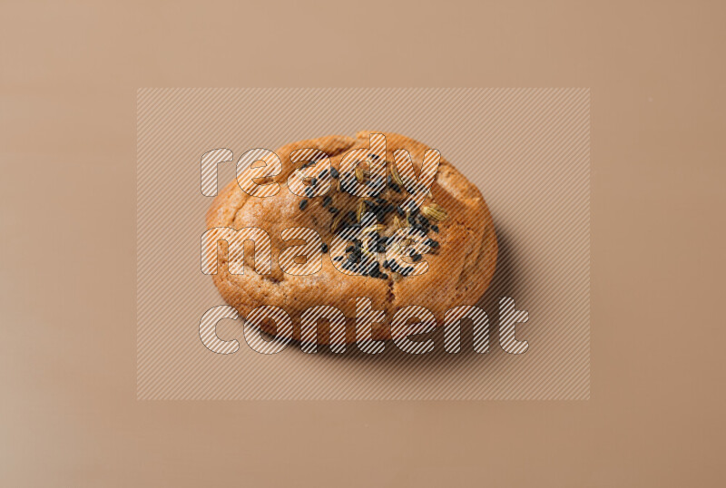 a whole Hasawi cookie with grains on a brown background
