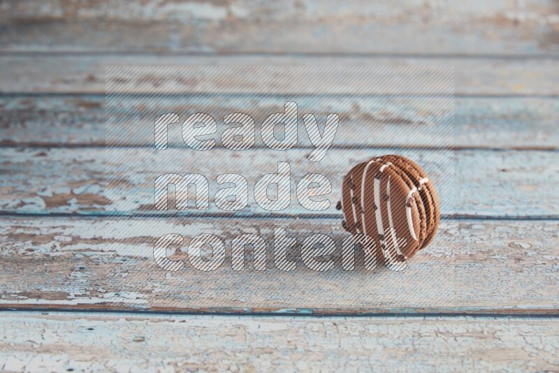 45º Shot of Brown white Chocolate Caramel macaron on light blue wooden background