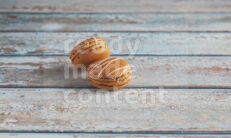 45º Shot of two Brown Irish Cream macarons on a  light blue wooden background