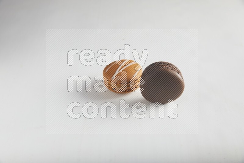 45º Shot of of two assorted Brown Irish Cream, and Brown Dark Chocolate macarons on white background