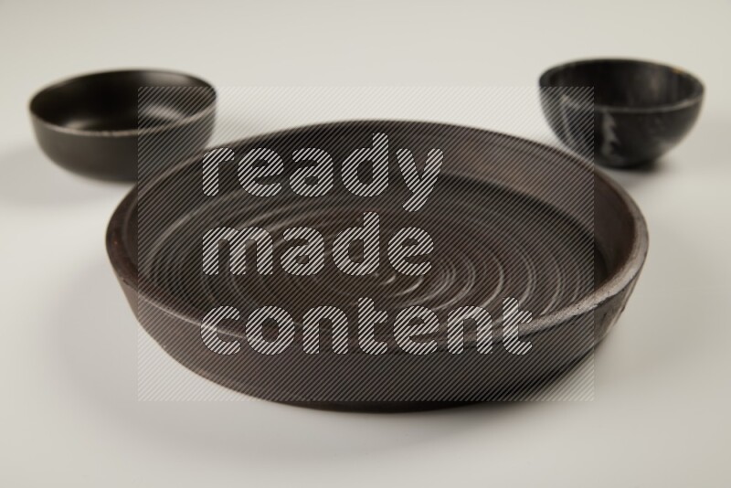 black pottery plate and black bowls on white background