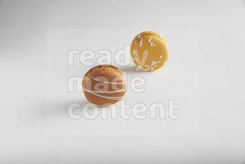 45º Shot of of two assorted Brown Irish Cream, and Yellow Piña Colada macarons on white background