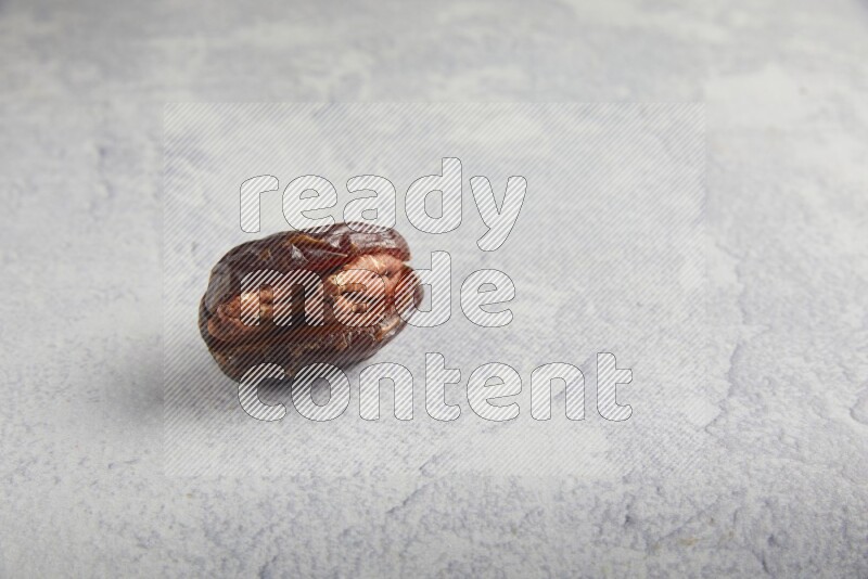 pecan stuffed madjoul date on a light grey background