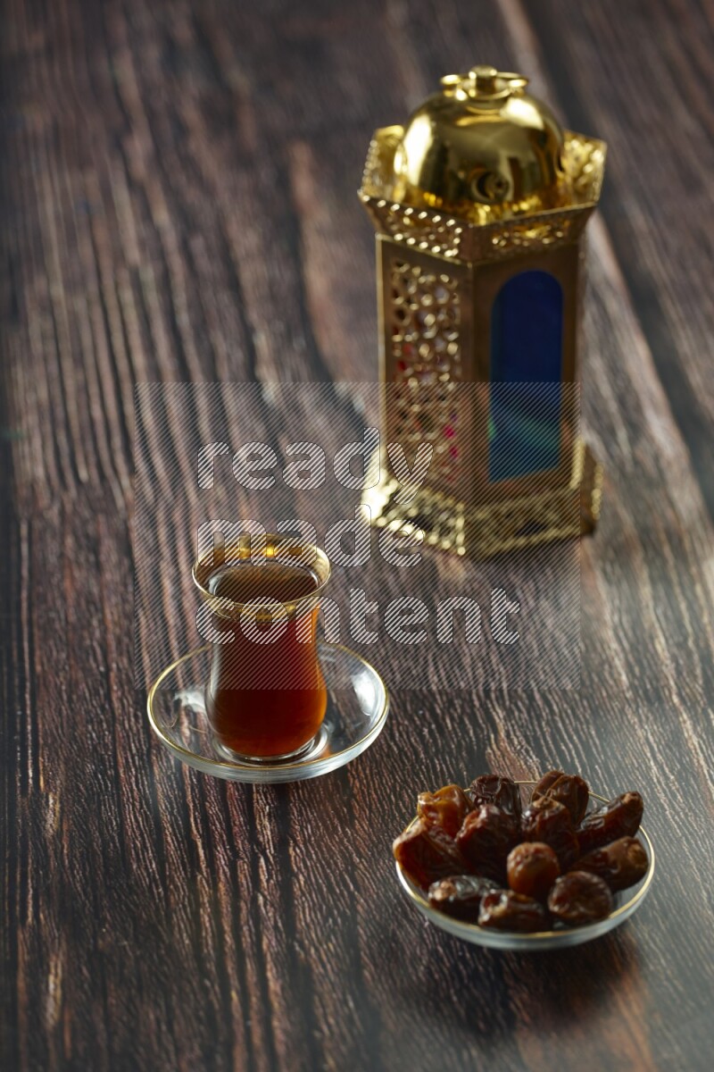 A golden lantern with different drinks, dates, nuts, prayer beads and quran on brown wooden background