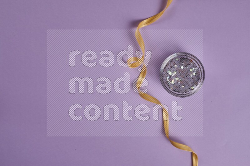 A yellow and purple collection of sewing and tailoring tools arranged on a purple background