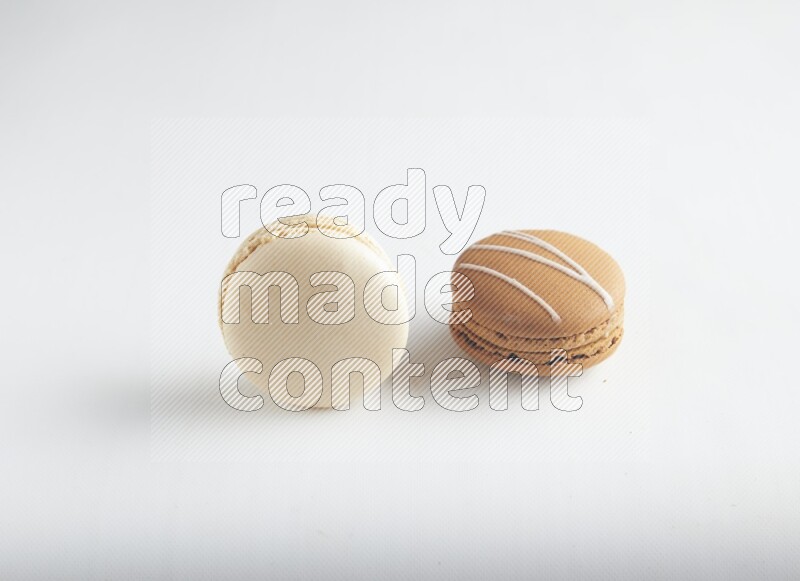 45º Shot of of two assorted Brown Irish Cream, and White Caramel fleur de sel macarons on white background