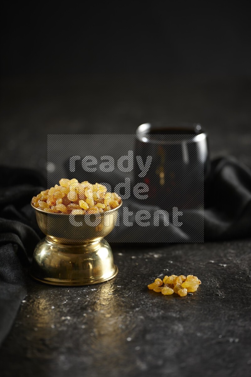 Dried fruits in a metal bowl with tamarind and a napkin in a dark setup