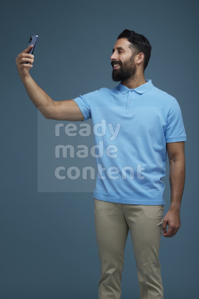 Man Taking a Selfie in a blue background wearing a Blue shirt
