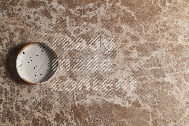 A multicolored pottery bowl on beige marble background