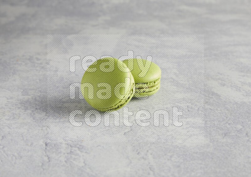 45º Shot of two Green Pistachio macarons  on white  marble background
