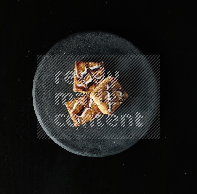 Assorted desserts in a black pottery plate on black background