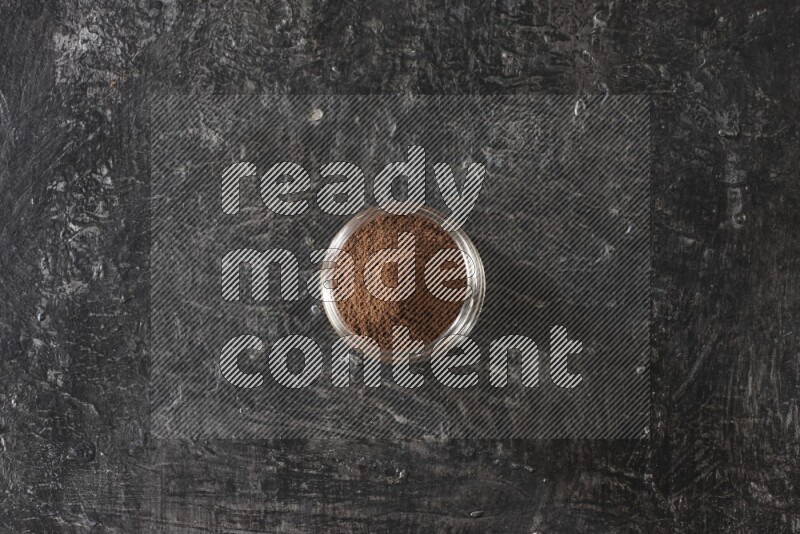 وعاء زجاجي ممتلئ ببودرة القرنفل على أرضية سوداء