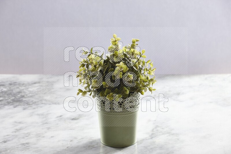 Artificial plant in green decorative pot on grey marble background