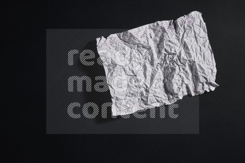 Crumpled notebook sheet on black background