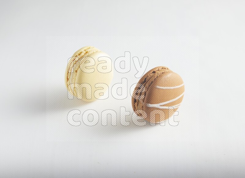 45º Shot of of two assorted Brown Irish Cream, and Yellow Vanilla macarons on white background