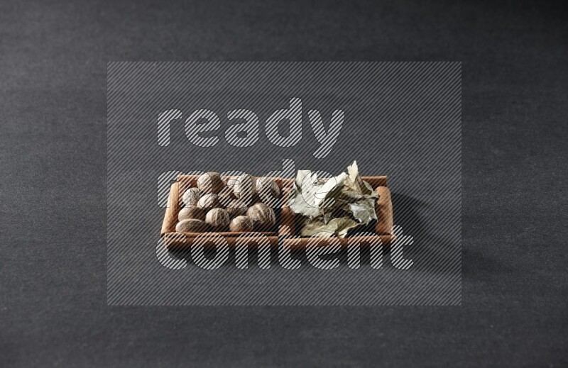 2 squares of cinnamon sticks full of nutmegs and bay laurel leaves on black flooring