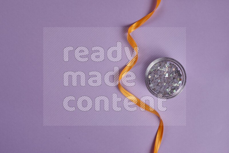 مجموعة من أدوات الخياطة والتفصيل برتقالية اللون على خلفية أرجوانية