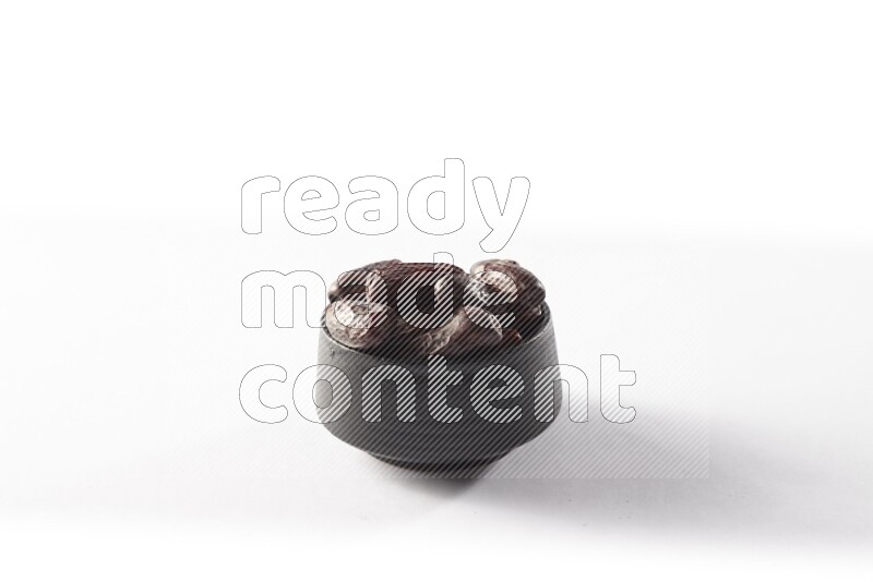 Dates in a black pottery bowl on white background