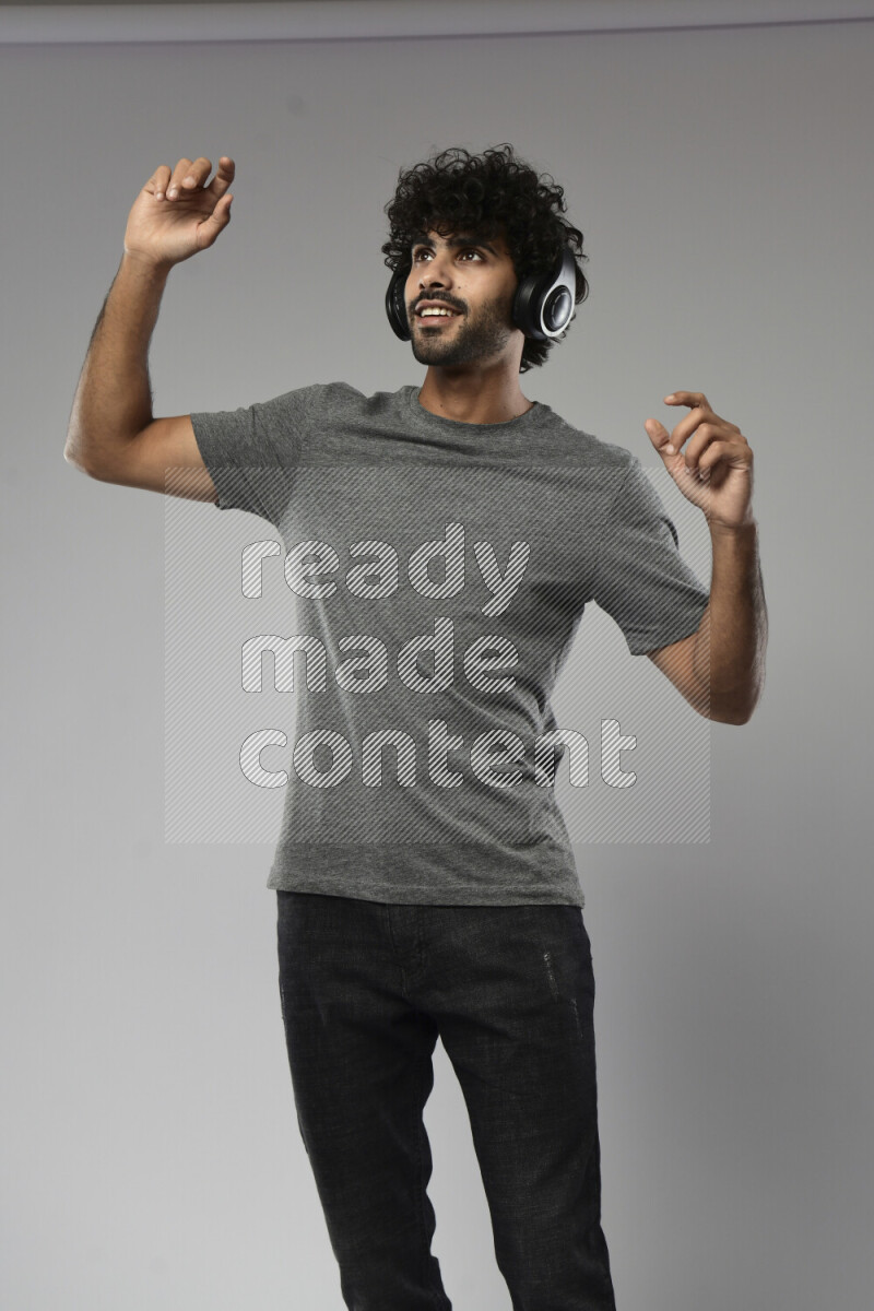 A man wearing casual standing and putting on headphones on white background