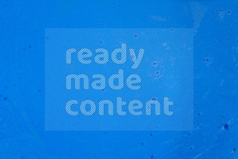 The image captures a dramatic splatter of blue paint over a blue backdrop